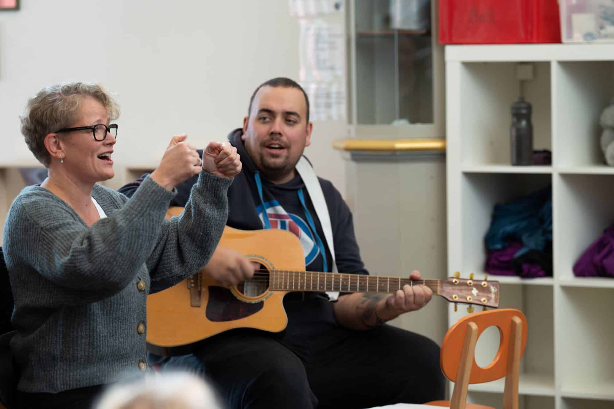 Bilde av to ansatte i Kråkeby Barnehage som spiller gitar og synger